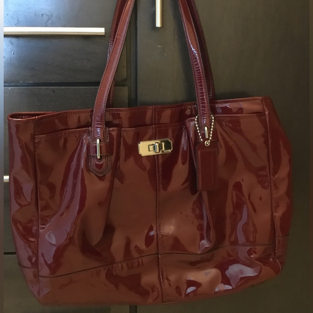 Coach crimson, patent leather bag with pink satin interior.
